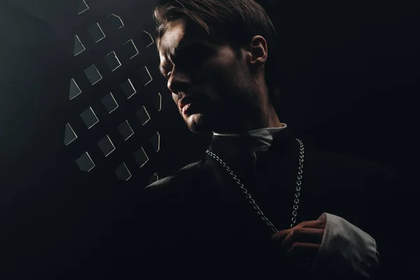 Joven Sacerdote Católico Serio Tocando Cruz Collar Parrilla Confesional Oscura — Foto de Stock