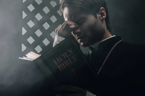 Junger Nachdenklicher Katholischer Priester Berührt Gesicht Beim Lesen Der Bibel — Stockfoto