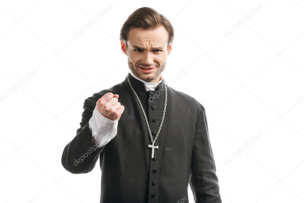 aggressive catholic priest showing fist while looking at camera isolated on white