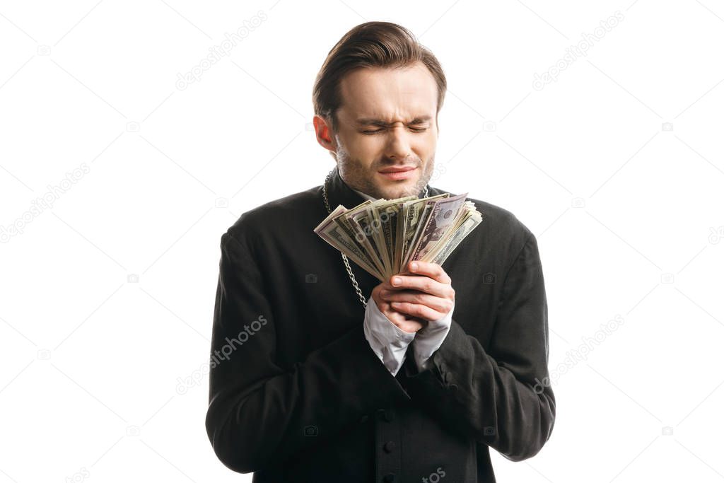 corrupt catholic priest with closed eyes holding dollar banknotes isolated on white