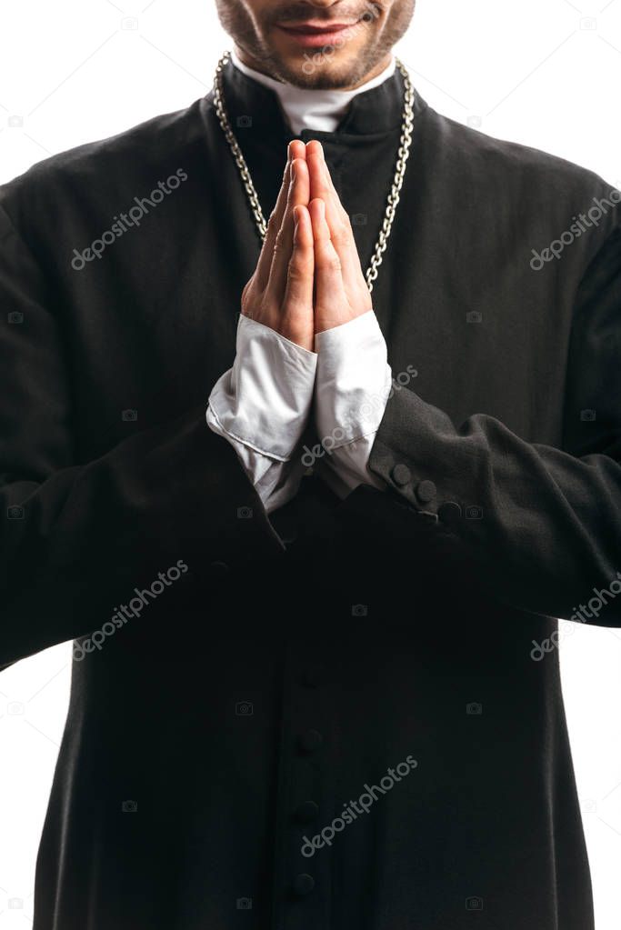 partial view of catholic priest in black cassock praying isolated on white