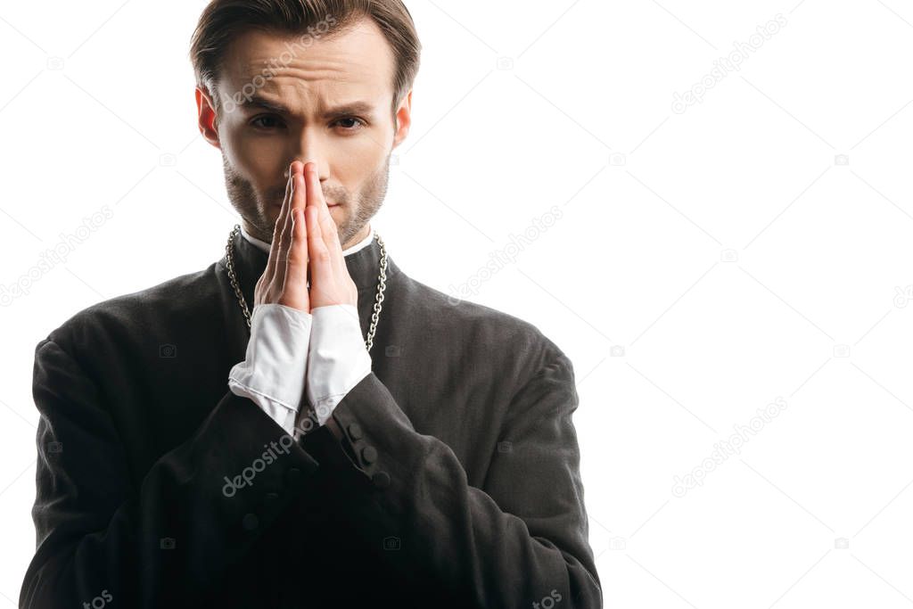 serious, concentrated catholic priest praying while looking at camera isolated on white