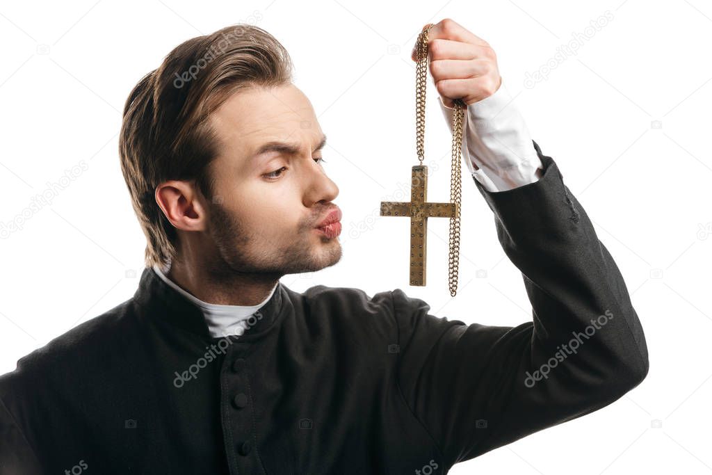 young insincere catholic priest going to kiss golden cross isolated on white