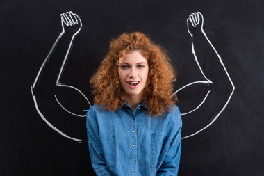 portrait of smiling redhead woman with strong muscular arms drawing on blackboard clipart