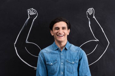 handsome smiling man with strong arms drawing on blackboard clipart