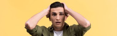 panoramic shot of worried young man, isolated on yellow
