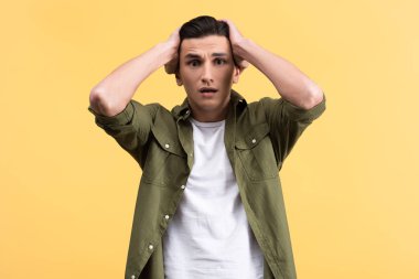 portrait of worried young man, isolated on yellow