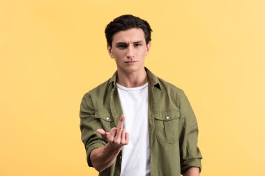 aggressive handsome man showing middle finger, isolated on yellow
