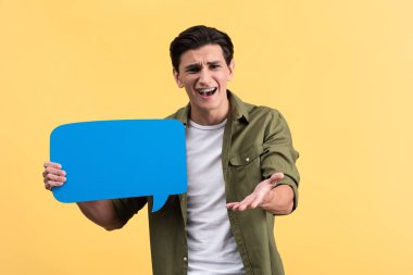 angry man holding blue speech bubble, isolated on yellow