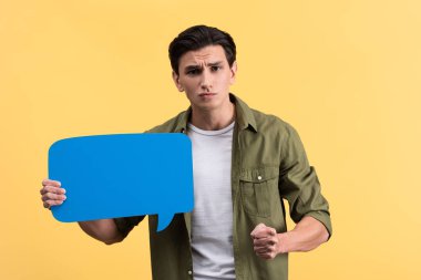 aggressive man holding fist and blue speech bubble, isolated on yellow