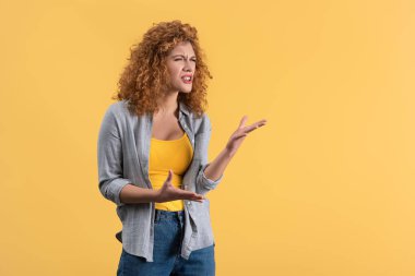 aggressive emotional redhead girl, isolated on yellow
