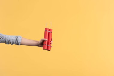 cropped view of woman holding dynamite in hand, isolated on yellow clipart