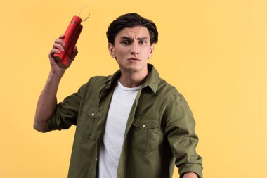 stressed young man holding dynamite sticks, isolated on yellow clipart