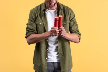 cropped view of angry man yelling and holding dynamite sticks, isolated on yellow clipart