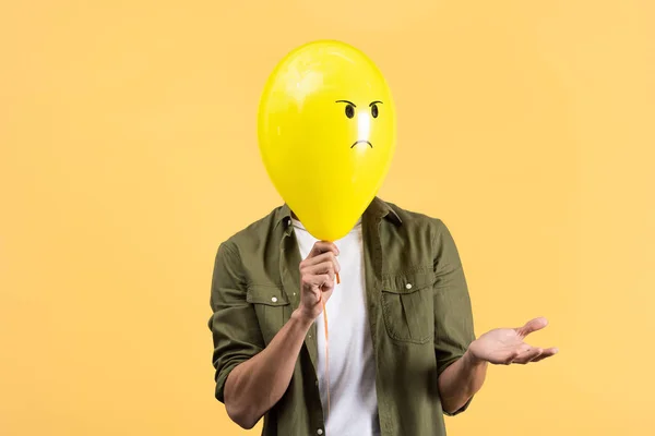Mladý Muž Pokrčením Ramen Drží Rozzlobený Balón Před Obličejem Izolovaný — Stock fotografie
