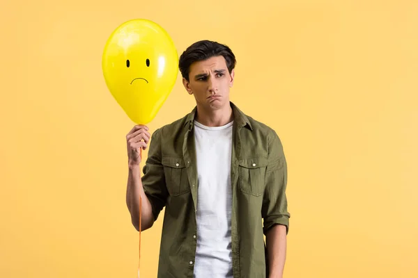 Rozrušený Mladý Muž Drží Smutný Balón Izolovaný Žluté — Stock fotografie