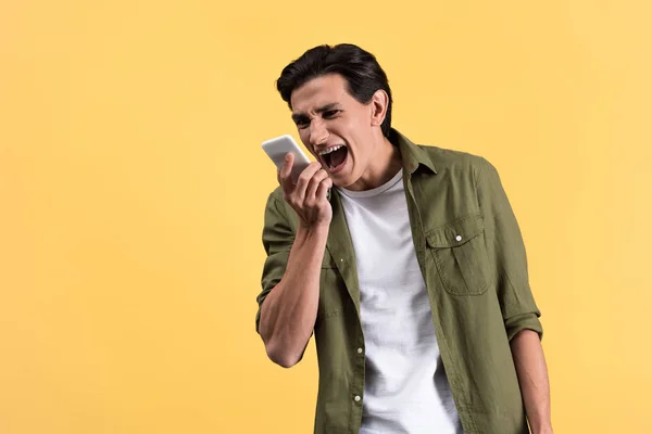 Θυμωμένος Νεαρός Άνδρας Ουρλιάζοντας Στο Smartphone Απομονωμένος Στο Κίτρινο — Φωτογραφία Αρχείου