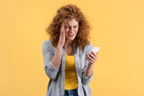 Zestresowana Ruda Kobieta Odczuwająca Ból Głowy Podczas Korzystania Smartfona Odizolowana — Zdjęcie stockowe