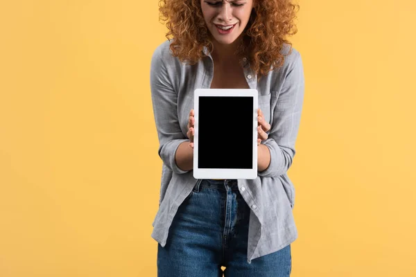 emotional girl showing digital tablet with blank screen, isolated on yellow