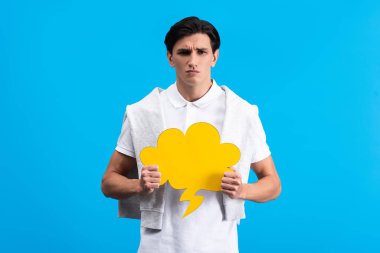 irritated man holding yellow cloud speech bubble, isolated on blue