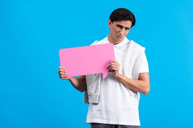upset man holding pink speech bubble, isolated on blue