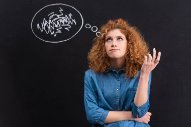thoughtful redhead young woman with thought bubble on blackboard