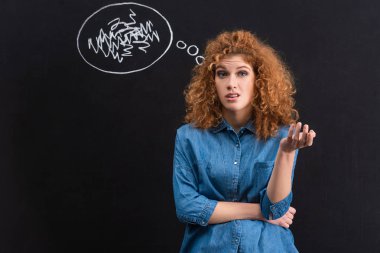 skeptical redhead young woman with thought bubble on chalkboard