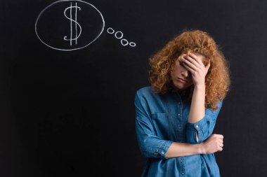 Kara tahtada dolar işareti olan düşünceli bir kız.