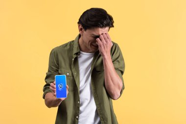 Kyiv, Ukrayna - 18 Kasım 2019: Shazam uygulamalı akıllı telefon gösteren endişeli adam, sarı ekranda izole edilmiş. 