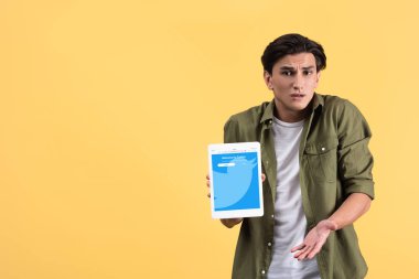 Kyiv, Ukrayna - 18 Kasım 2019: omuz silkme hareketli duygusal adam ekranda twitter uygulamalı dijital tablet gösteriyor, sarı üzerinde izole edilmiş. 