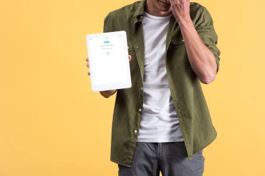 Kyiv, Ukrayna - 18 Kasım 2019: Ekranda Skype uygulamalı dijital tablet gösteren adamın görüntüsü, sarı ekranda izole edilmiş 