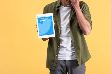 Kyiv, Ukrayna - 18 Kasım 2019: Ekranda twitter uygulaması ile dijital tablet gösteren, sarı üzerine izole edilmiş bir adam görüntüsü 