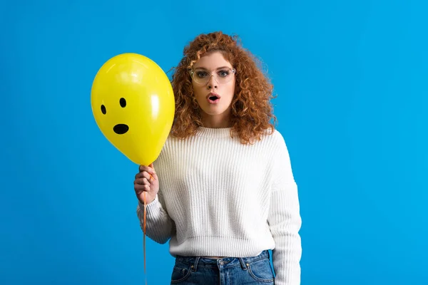 Menina Chocada Segurando Balão Amarelo Com Rosto Surpreso Isolado Azul — Fotografia de Stock