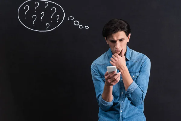 Nachdenklicher Junger Mann Mit Smartphone Mit Fragezeichen Gedankenblase Auf Tafel — Stockfoto