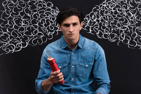 angry young man holding dynamite, with steam drawing on chalkboard