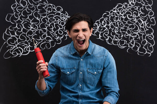 angry young man shouting and holding dynamite, with steam drawing on blackboard