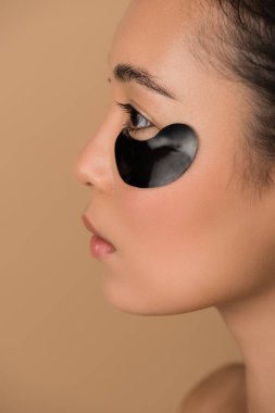 Siyah hidrojeli göz bandı olan güzel Asyalı kız profili bej renkte izole edilmiş.