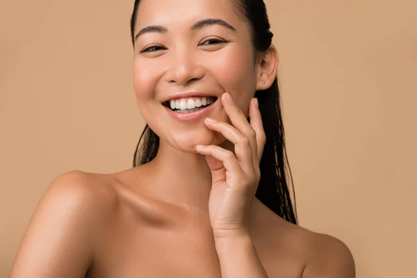 微笑美丽的赤裸裸的亚洲女孩触摸着被米色隔离的脸 — 图库照片