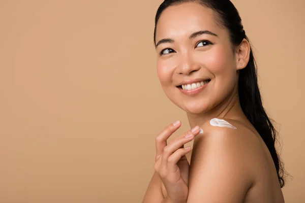Mosolygós Gyönyörű Meztelen Ázsiai Lány Kozmetikai Krém Vállán Elszigetelt Bézs — Stock Fotó
