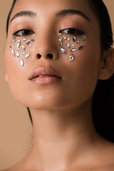 beautiful naked asian girl with rhinestones on face isolated on beige