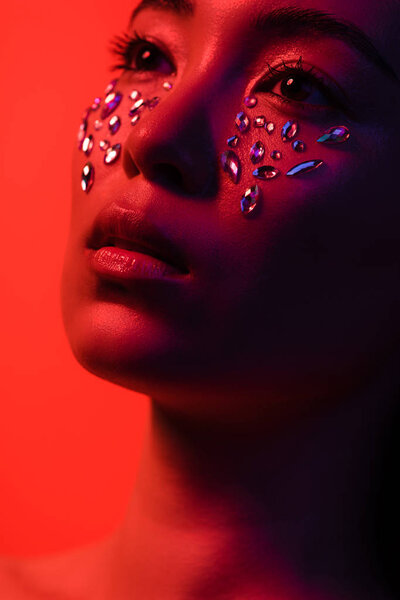 beautiful asian girl with rhinestones on face isolated on red