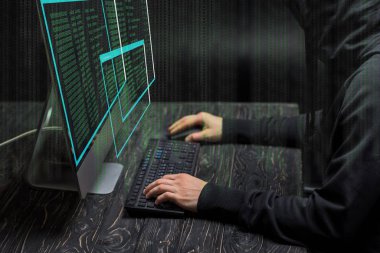 Bilgisayar ekranının yanında bilgisayar klavyesinde siyah verilerle yazılan bilgisayar korsanının kırpılmış görünümü 