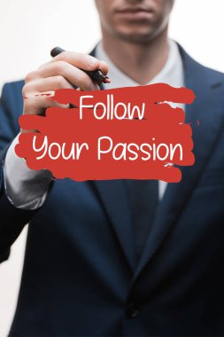 selective focus of businessman in formal wear holding marker pen near follow your passion lettering on white  clipart