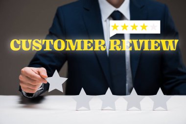 cropped view of businessman holding star near customer review lettering on grey, quality concept  clipart