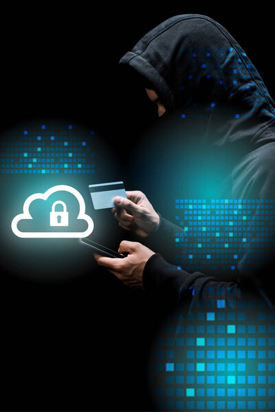 hacker in hood and mask using smartphone and holding credit card near cloud with padlock illustration on black 