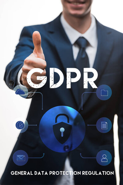 selective focus of happy businessman in suit showing thumb up near gdpr lettering on white 