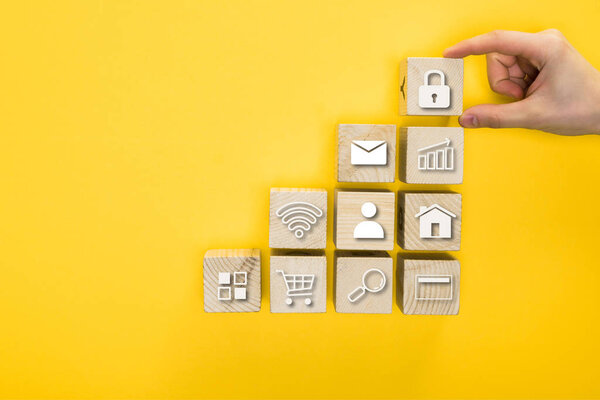 top view of man holding wooden cube with padlock isolated on yellow 
