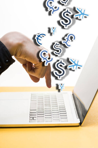 cropped view of man pointing with finger at laptop near money symbols on white 