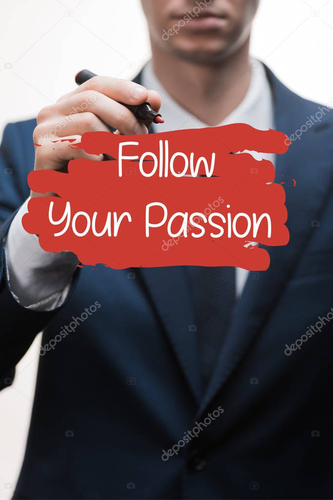 selective focus of businessman in formal wear holding marker pen near follow your passion lettering on white 