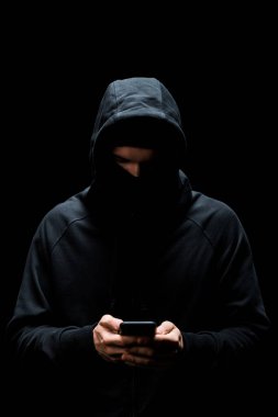 Siyahta izole edilmiş akıllı telefon kullanarak mahalledeki hacker. 